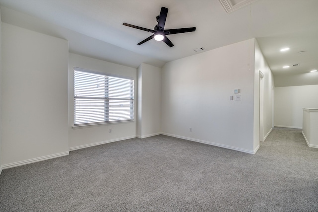 unfurnished room featuring carpet flooring, attic access, a ceiling fan, baseboards, and vaulted ceiling