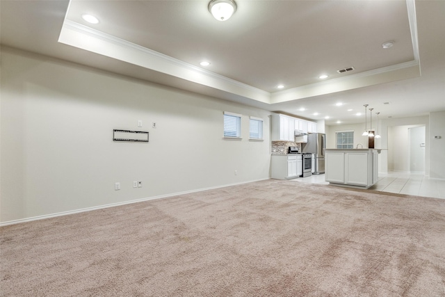 unfurnished living room with crown molding, a tray ceiling, light colored carpet, and visible vents