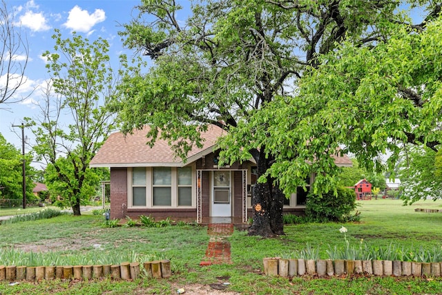 view of front of house featuring brick siding, roof with shingles, and a front lawn