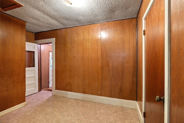 unfurnished room featuring tile patterned floors, wood walls, and a textured ceiling