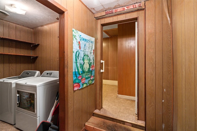 washroom with laundry area, wood walls, and washing machine and clothes dryer