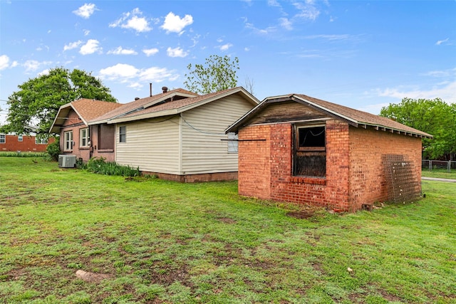 rear view of property featuring brick siding, fence, a yard, and cooling unit