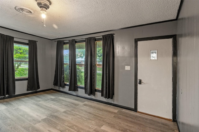foyer featuring baseboards, light wood finished floors, a textured ceiling, and visible vents