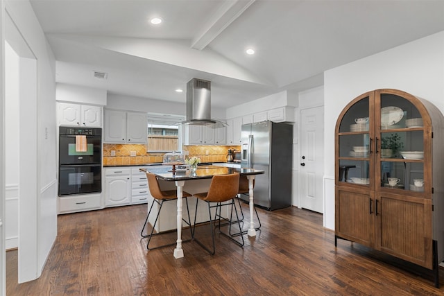 kitchen featuring backsplash, a kitchen bar, visible vents, island range hood, and appliances with stainless steel finishes