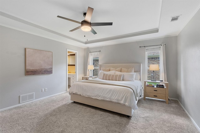 bedroom featuring a tray ceiling, visible vents, and carpet