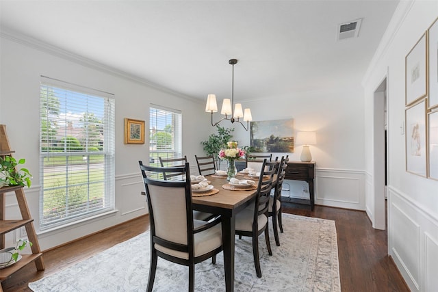 dining room featuring visible vents, crown molding, wood finished floors, a wainscoted wall, and a chandelier