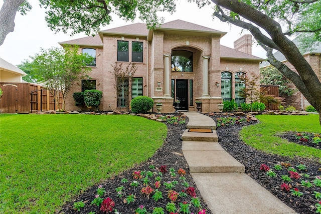 view of front of home featuring a gate, fence, brick siding, and a front yard