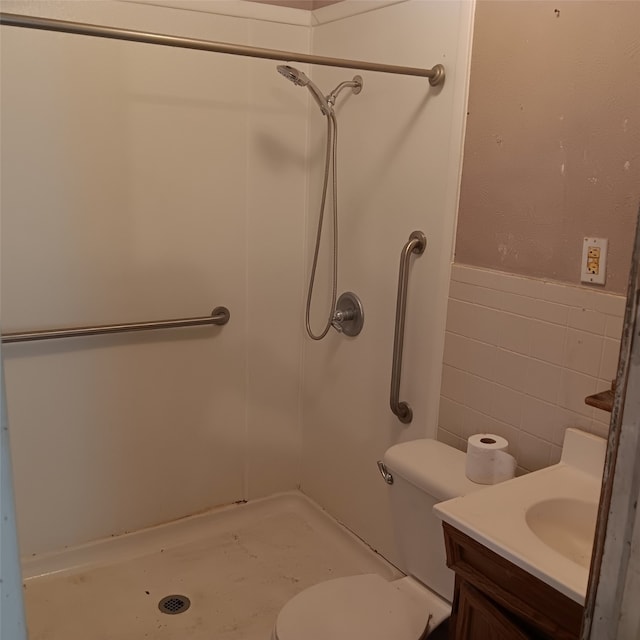 bathroom with tile walls, a stall shower, vanity, a wainscoted wall, and toilet
