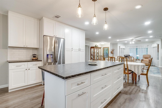 kitchen featuring a ceiling fan, stainless steel refrigerator with ice dispenser, visible vents, dark countertops, and light wood-style flooring