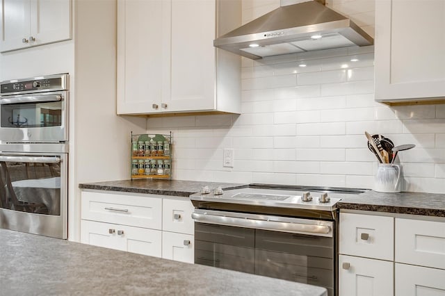 kitchen with white cabinetry, stainless steel double oven, range hood, and tasteful backsplash
