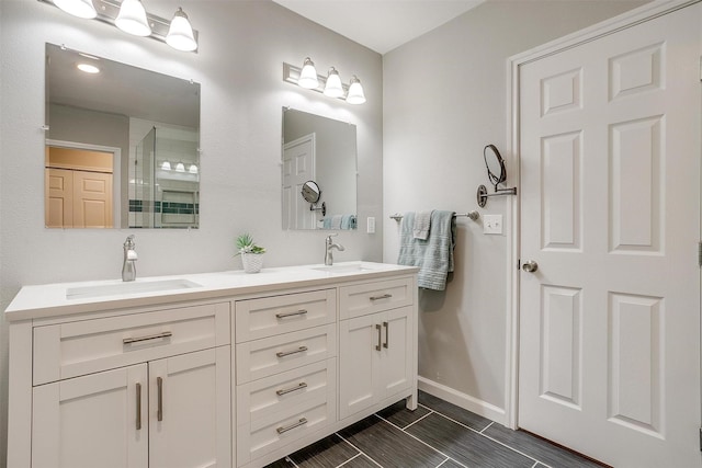 full bath with double vanity, a sink, baseboards, and tile patterned flooring
