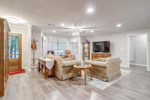 living room featuring crown molding, baseboards, visible vents, and light wood-style floors