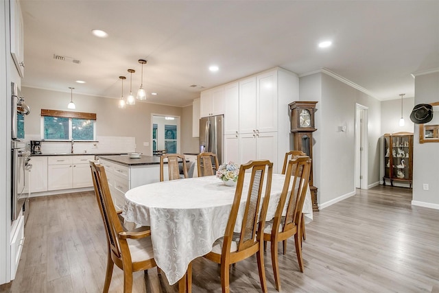 dining space featuring crown molding, light wood-style flooring, recessed lighting, baseboards, and visible vents