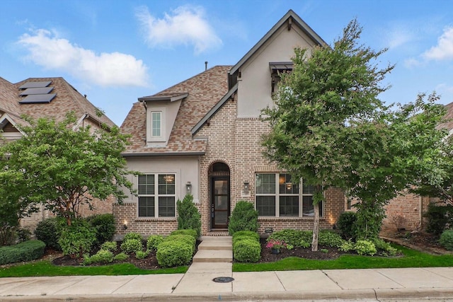 english style home featuring stucco siding and brick siding