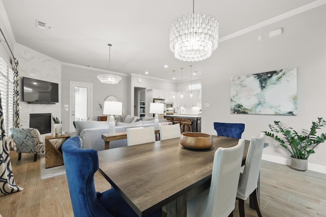dining space with light wood-type flooring, ornamental molding, and a chandelier