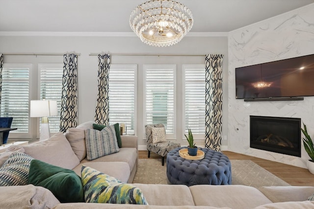living room featuring ornamental molding, wood finished floors, a notable chandelier, and a fireplace