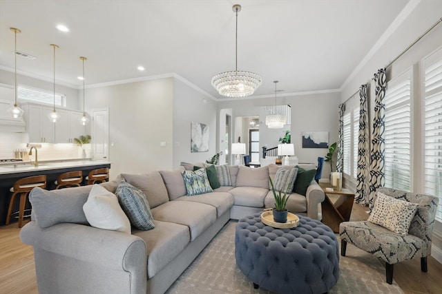 living area featuring crown molding, light wood-style floors, a chandelier, recessed lighting, and visible vents