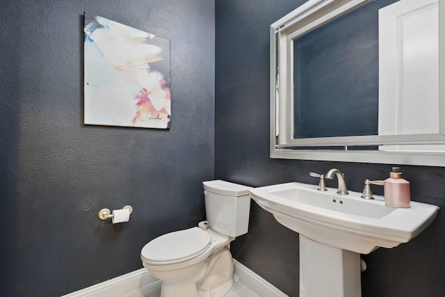 bathroom with toilet, baseboards, and a sink