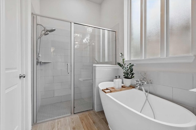 full bath featuring wood finished floors, a freestanding tub, and a stall shower