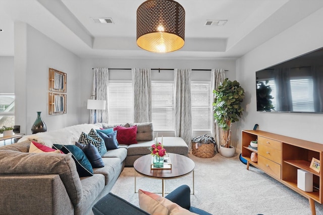 living area featuring carpet floors, a tray ceiling, and visible vents