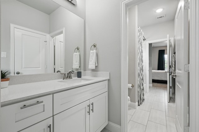 ensuite bathroom featuring visible vents, vanity, toilet, baseboards, and ensuite bath