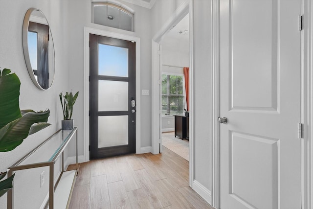 entryway with baseboards, light wood finished floors, and crown molding