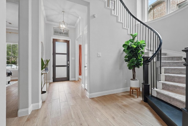 foyer with an inviting chandelier, stairs, and light wood finished floors