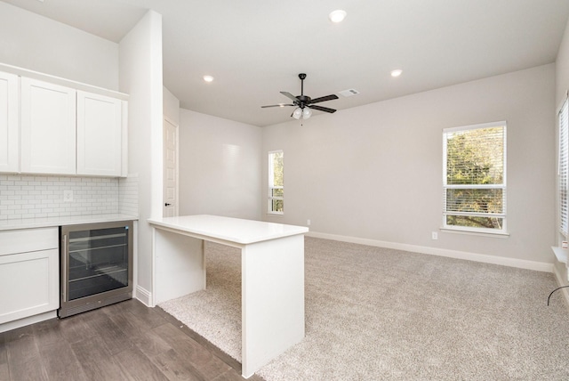 kitchen with light countertops, plenty of natural light, a peninsula, wine cooler, and visible vents