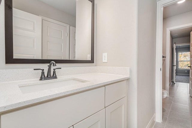bathroom with toilet, tile patterned floors, baseboards, and vanity