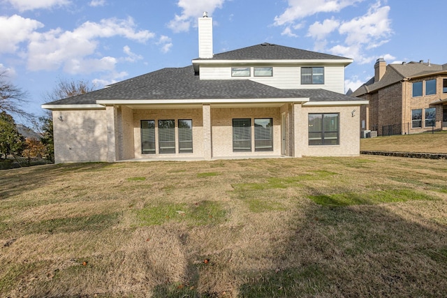 back of house with a yard, brick siding, and a chimney