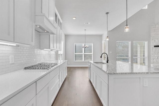 kitchen featuring dark wood-type flooring, white cabinetry, a sink, backsplash, and stainless steel appliances