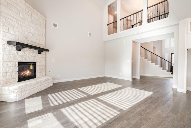 unfurnished living room with stairs, a high ceiling, baseboards, and wood finished floors