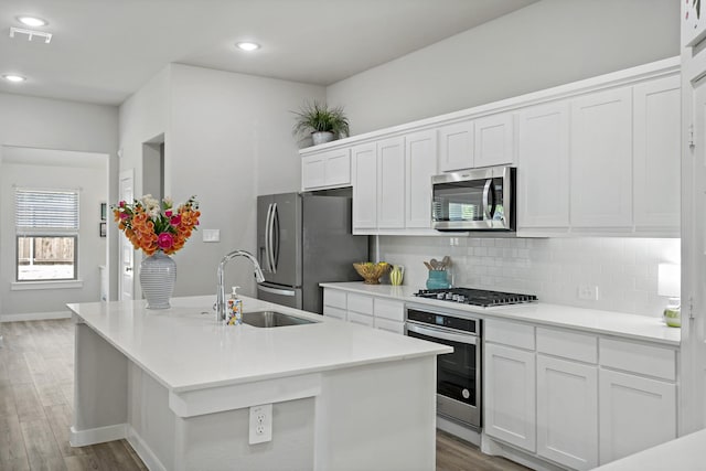 kitchen featuring a sink, decorative backsplash, stainless steel appliances, and wood finished floors