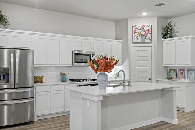 kitchen featuring visible vents, a sink, light countertops, stainless steel appliances, and light wood-style flooring
