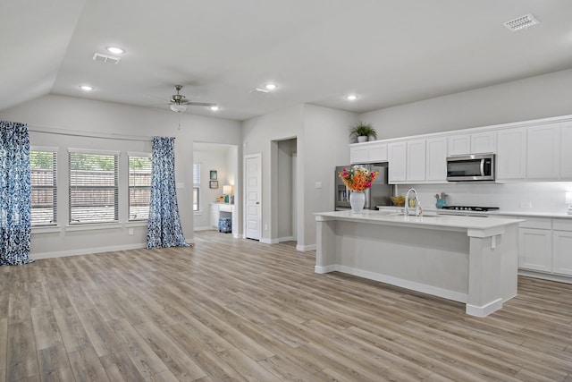 kitchen with visible vents, open floor plan, light countertops, a sink, and appliances with stainless steel finishes
