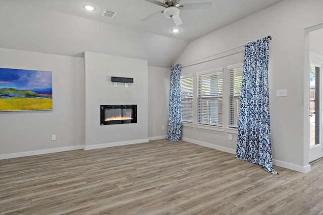 unfurnished living room featuring visible vents, a glass covered fireplace, wood finished floors, and vaulted ceiling