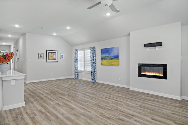 unfurnished living room with a glass covered fireplace, visible vents, light wood-type flooring, and lofted ceiling