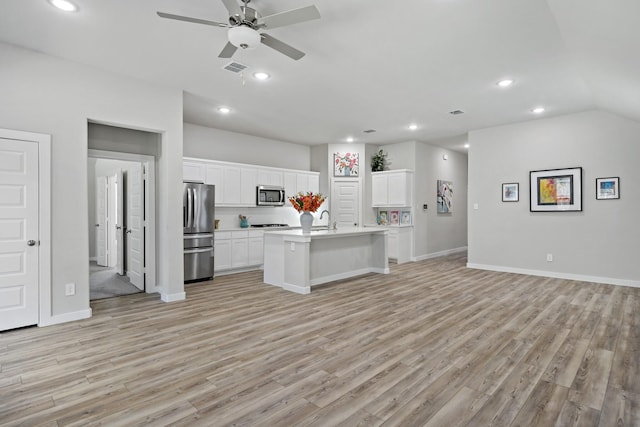 kitchen with appliances with stainless steel finishes, light wood-style floors, light countertops, a ceiling fan, and open floor plan