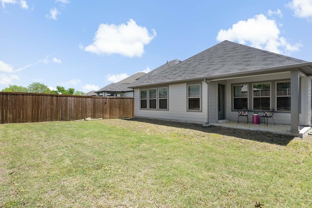 rear view of property with a lawn, fence, and roof with shingles