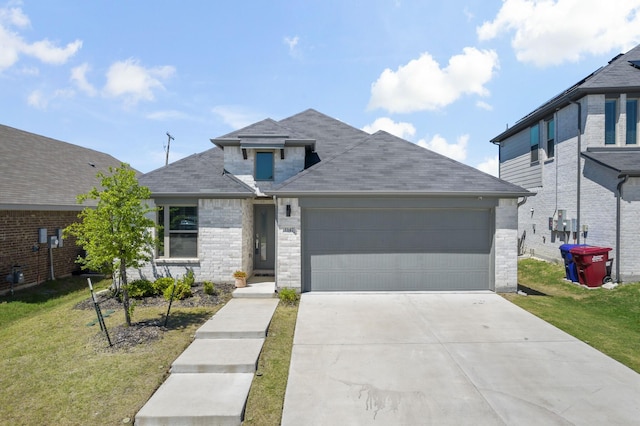 view of front of house with driveway, roof with shingles, a garage, brick siding, and a front lawn