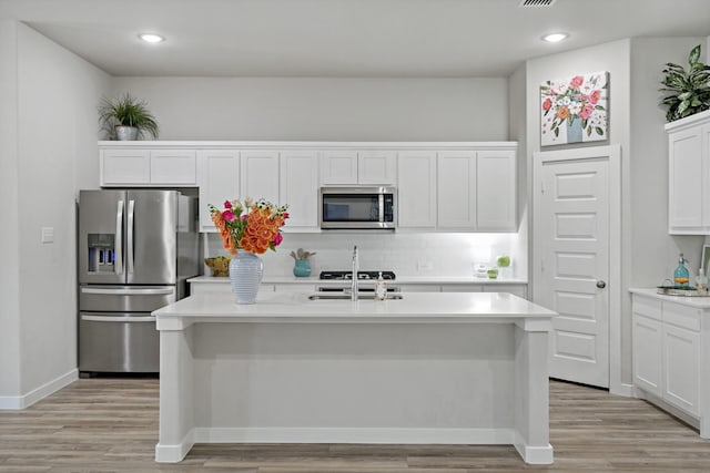 kitchen with a sink, light wood finished floors, appliances with stainless steel finishes, and light countertops