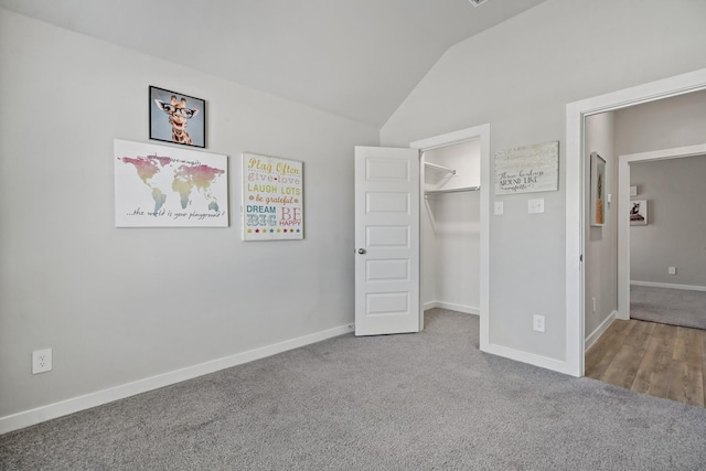 unfurnished bedroom with carpet floors, baseboards, vaulted ceiling, and a spacious closet