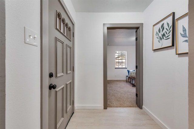 hall featuring baseboards and light wood-style flooring