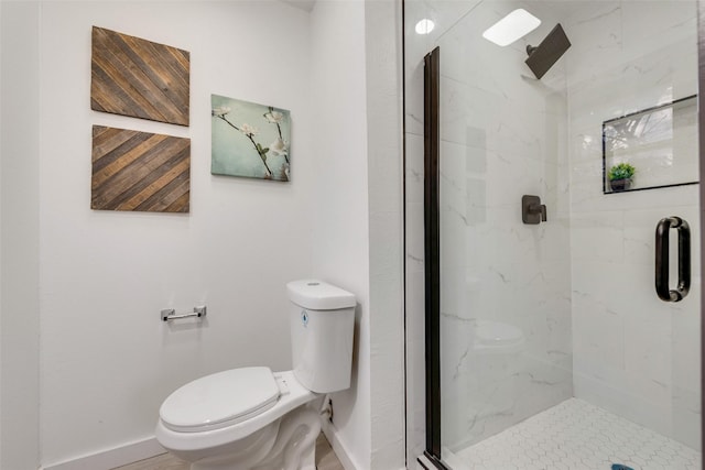 bathroom featuring baseboards, a marble finish shower, and toilet