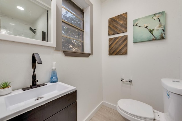 bathroom with baseboards, toilet, and vanity