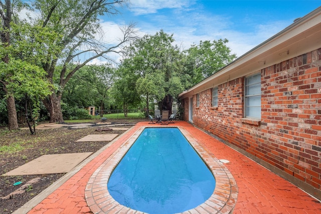 outdoor pool with fence and a patio area