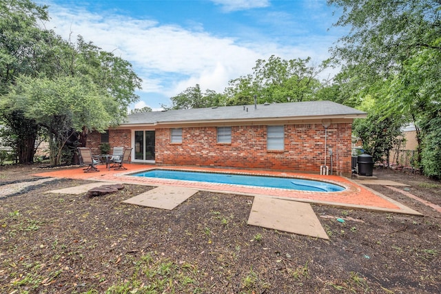 rear view of property featuring a patio area, an outdoor pool, and brick siding