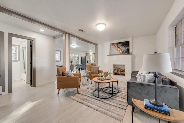 living area with baseboards, visible vents, wood finished floors, and a fireplace