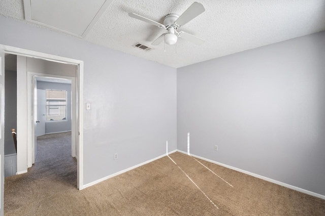 empty room with ceiling fan, carpet flooring, a textured ceiling, and visible vents