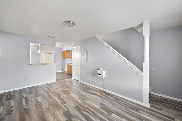 unfurnished living room with stairway, baseboards, wood finished floors, and visible vents